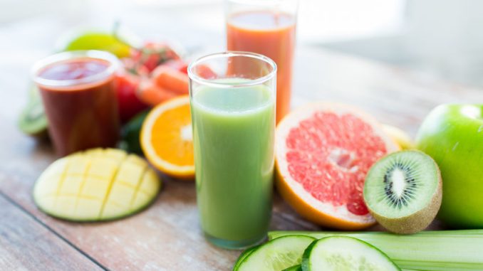 close up of fresh juice glass and fruits on table